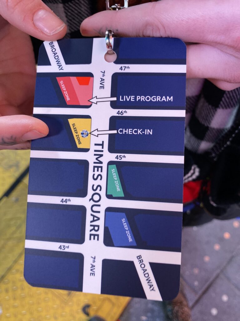 Hands holding a Times Square sleep zone map badge showing locations for the World's Big Sleep Out event